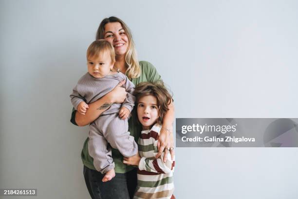 portrait of young woman happy family mother with sons on grey background - famiglia con due figli foto e immagini stock