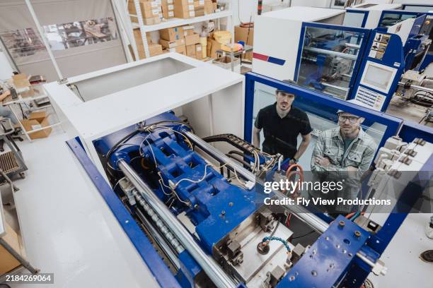 due uomini che utilizzano la macchina per lo stampaggio ad iniezione di materie plastiche nell'impianto di fabbricazione - plasma foto e immagini stock