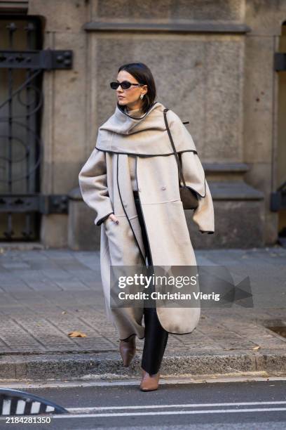 Zina Charkoplia wears brown NEOUS boots, ALMADA sweater, black LAMARQUE leather pants, grey COS coat with cape, PODYH bag on November 11, 2024 in...