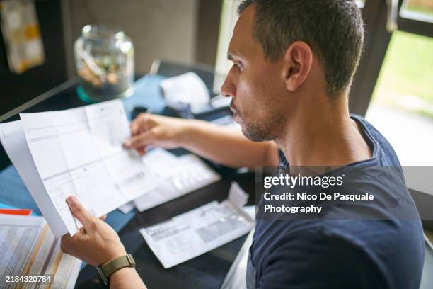 man preparing his taxes at home - busta paga foto e immagini stock