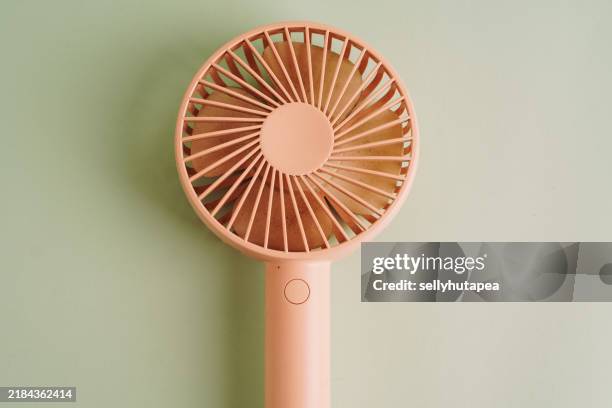 portable pink handy fan on pale green background - hand fan stock pictures, royalty-free photos & images