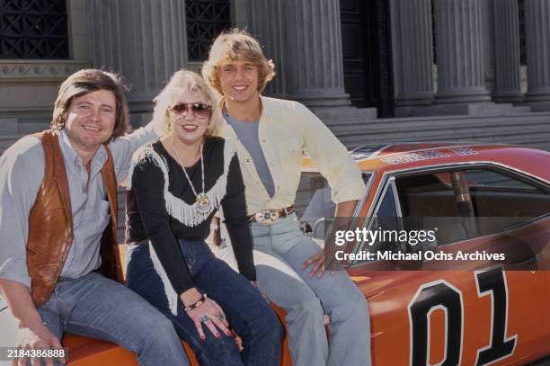 American actor, and politician Ben Jones, wearing a brown leather waistcoat over a blue shirt with rolled-up sleeves and jeans, beside a woman who...