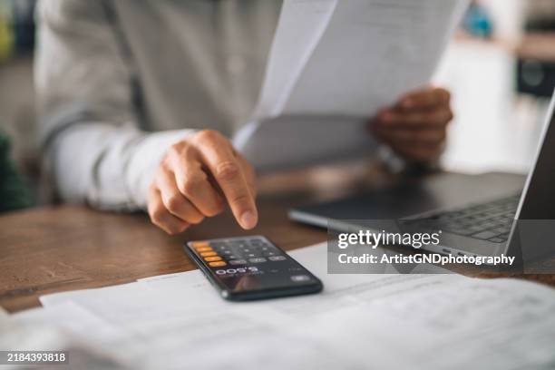 close-up of a man calculating his monthly expenses at home. - calculator stock pictures, royalty-free photos & images