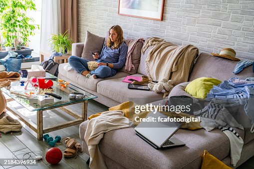 Lazy teenager watching TV sitting on the sofa of a messy living room Lazy teenager watching TV sitting on the sofa of a messy living room