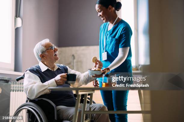 caregiver sharing a moment with elderly man in wheelchair - residential care stock pictures, royalty-free photos & images