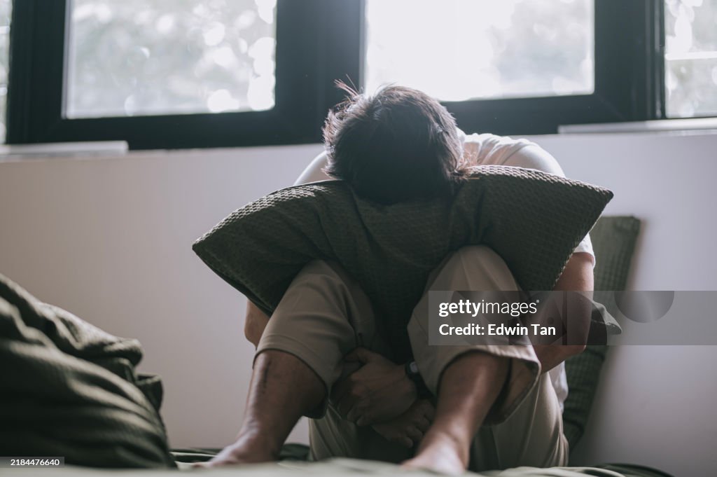 Homme chinois asiatique triste assis sur le lit