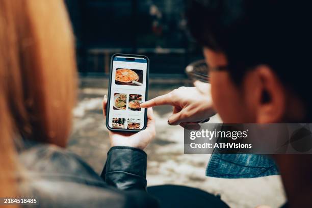 friends using mobile food delivery app to browse menu and order online - ordering stock pictures, royalty-free photos & images