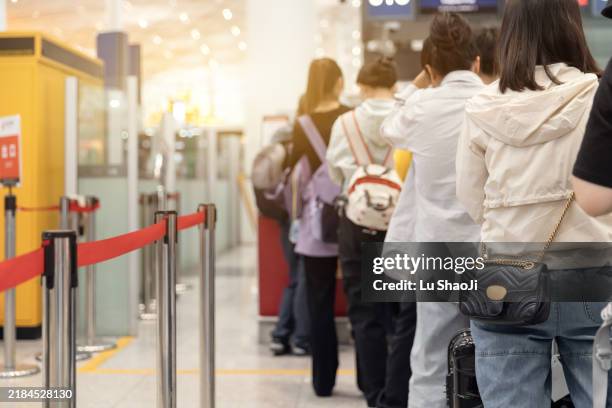 passengers lined up at the airport to check in their luggage. - esperar na fila imagens e fotografias de stock