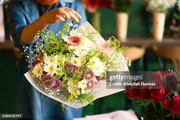 main de femme préparant un bouquet dans un magasin de fleurs - composition florale photos et images de collection