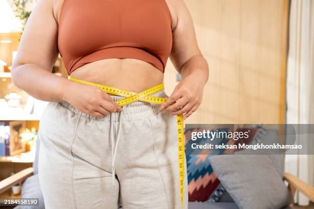 close up shot at hand of women while use measure tape with her tummy or waist belly of chubby women that show sign of overweight. on white background with copy space for text - abdomen humano fotografías e imágenes de stock