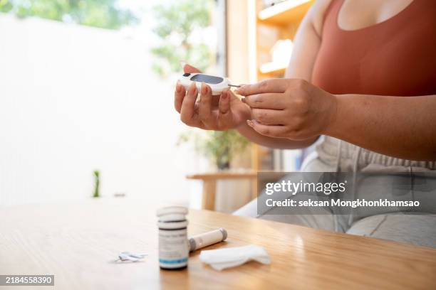 a young woman is using a glucometer - hypoglycemia stock pictures, royalty-free photos & images
