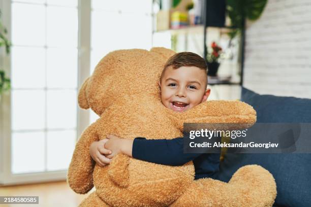 cute joyful boy smiling and hugging his new teddy bear not wanting to separate from it - big hug stock pictures, royalty-free photos & images