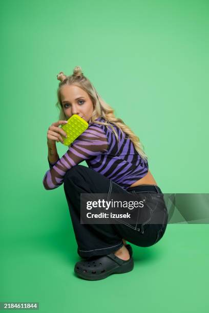 portrait of gen z young woman holding smart phone - lichaamshouding stockfoto's en -beelden
