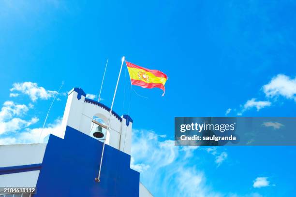 spanish flag weaving against blue sky with clouds - spanische flagge stock-fotos und bilder