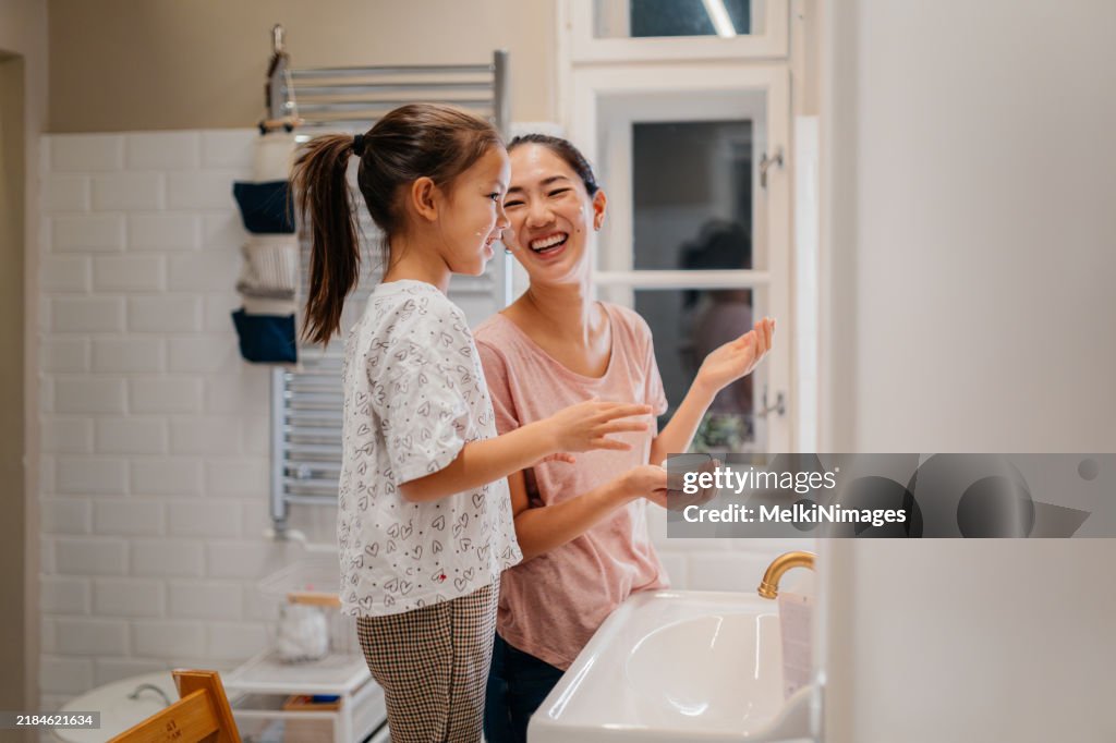 Happy family! Mother and daughter child girl are caring for skin in the bathroom.