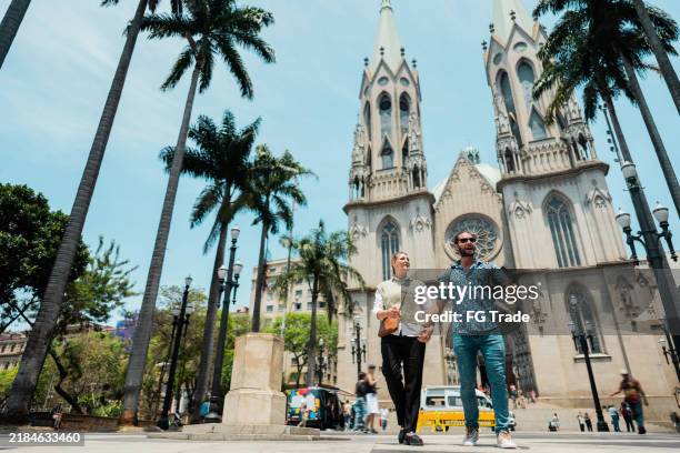 jeune couple de touristes discutant en marchant sur la place sé, à são paulo, brésil - são paulo photos et images de collection