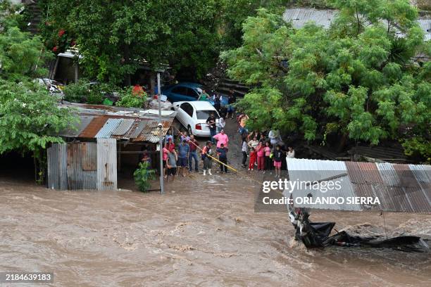 People look at the flooding of the Choluteca river in Tegucigalpa on November 17 due to the heavy rains left by tropical storm Sara. Tropical storm...