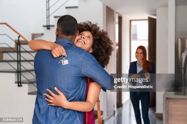 couple d’amour achetant une maison et célébrant avec un câlin - annonce immobilière photos et images de collection