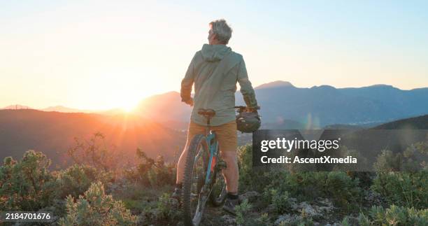 mature mountain biker rides hills at sunrise - cyklist bildbanksfoton och bilder