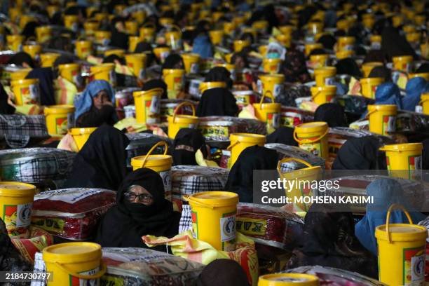 Afghan women sit next to food and winter blankets distributed by a local charity foundation in Injl district of Herat province on November 18, 2024.