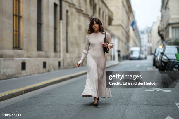 Ellie Delphine wears a beige stripped long dress, a black leather bag, black leather ballerinas shoes, during a street style fashion photo session,...