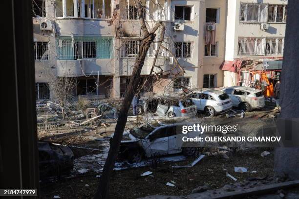 Local residents inspect damage to a residential building and cars following a missile attack in Odesa on November 18, 2024. The toll from a Russian...