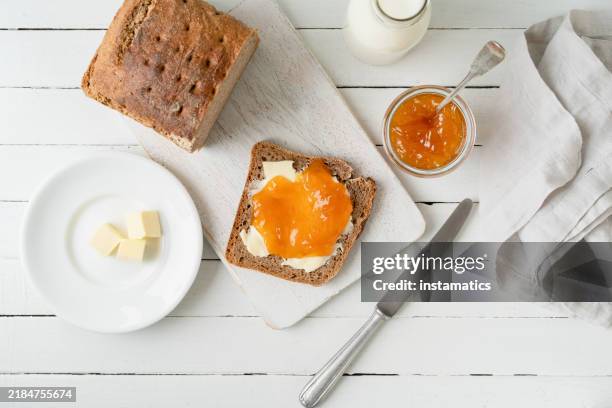 whole grain bread with apricot jam on a white cutting board - marmellata di agrumi foto e immagini stock