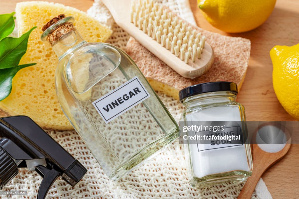 Natürliche und umweltfreundliche Haushaltsreiniger: Natron, weißer Essig, Zitrone, Scheuerbürste und Reinigungsschwamm