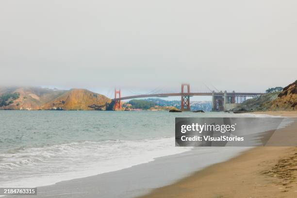morgen am baker beach mit blick auf die von wolken bedeckte golden gate bridge in san francisco city - golden gate park stock-fotos und bilder