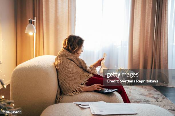 woman with cerebral palsy managing home finance using a calculator. she's working on her utility bill and calculating her house expenses - energy bill stock pictures, royalty-free photos & images