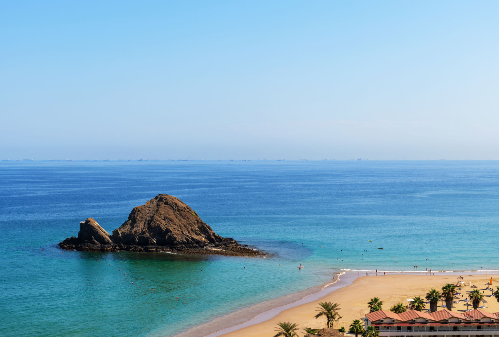 Snoopy Island in Fujairah, UAE. Aerial view of the beach with turquoise waters, a rocky island and a resort nearby Snoopy Island in Fujairah, UAE. Aerial view of the beach with turquoise waters, a rocky island and a resort nearby