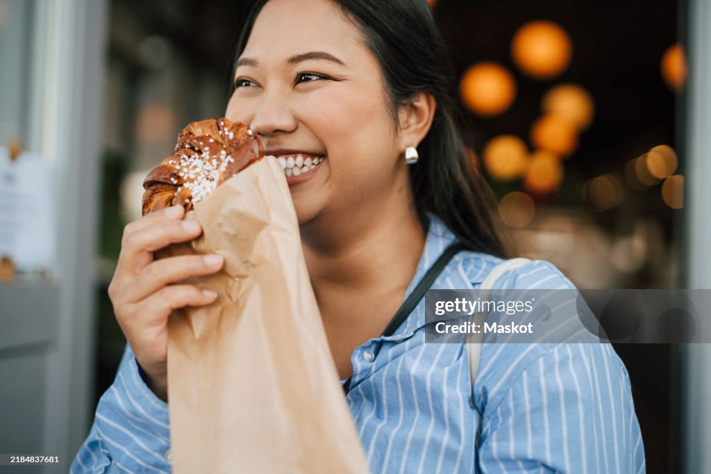Happy young woman holding fresh cinnamon bun