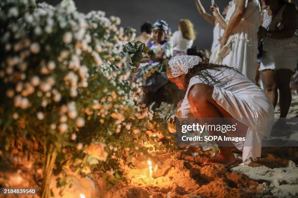 Believer lights a candle as an offering during the Festival of Iemanjá. Every year, on December 31st and February 2nd, crowds gather along Brazilian...