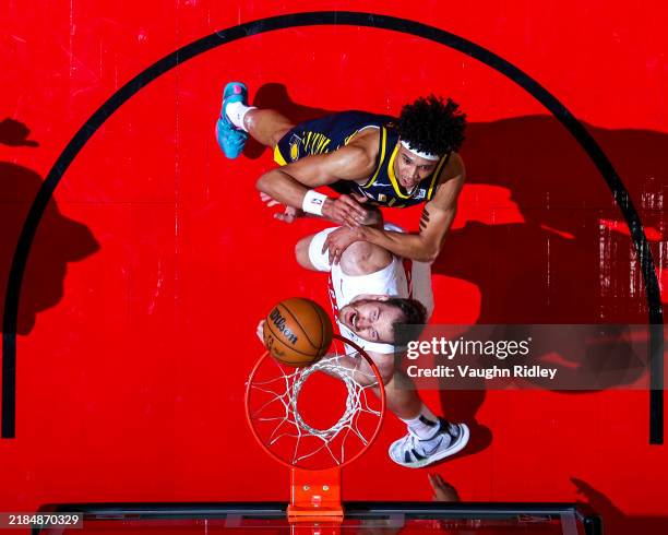 Jakob Poeltl of the Toronto Raptors and Enrique Freeman of the Indiana Pacers wait for a rebound during the game on November 18, 2024 at the...