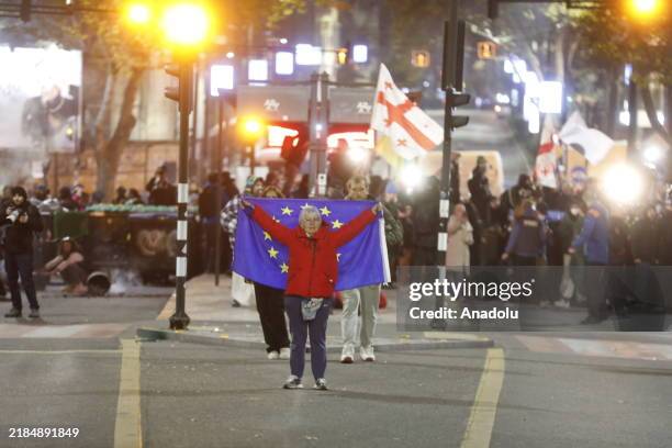 Man waves a Georgian flag as the police and special forces clear the area from the Georgian opposition protesters after protesters set up tents...