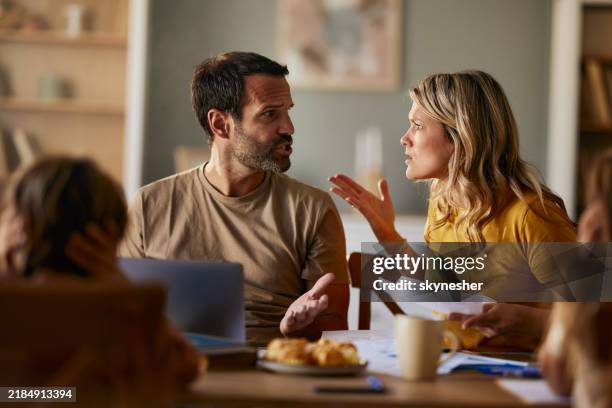des parents mécontents qui se disputent en payant leurs factures sur un ordinateur portable à la maison. - se disputer photos et images de collection