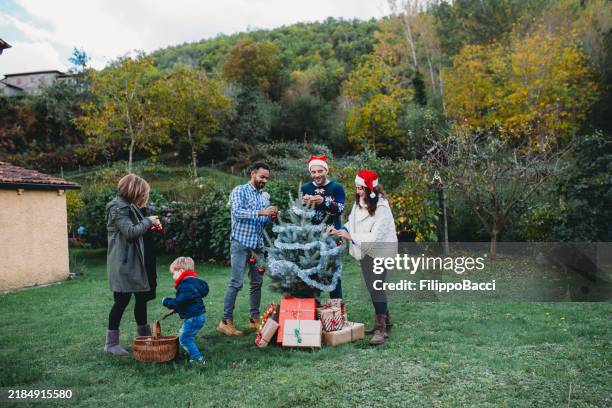 family decorating christmas tree together in garden - decorating the christmas tree stock pictures, royalty-free photos & images