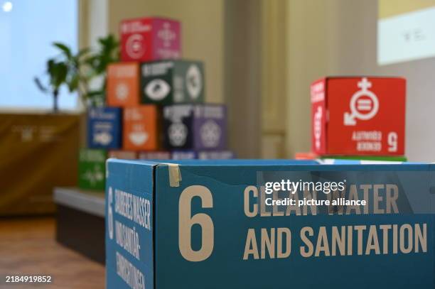 November 2024, Berlin: Cubes with the UN Sustainable Development Goals stand next to and on the stage at the Toilet Congress; the words "Clean Water...