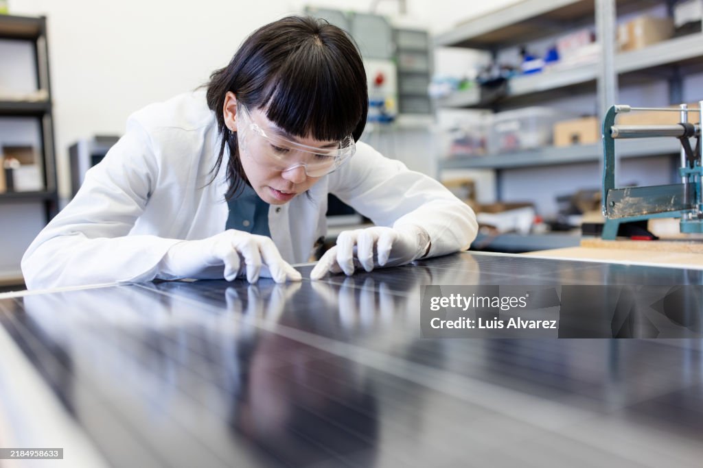 Woman technician studying solar panel module in modern agricultural laboratory