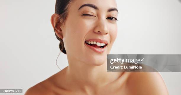 woman, beauty and skincare with wink in studio portrait for results, glow and transformation by white background. person, model and smile with funny face for wellness, cosmetics and emoji in portugal - winking stock pictures, royalty-free photos & images