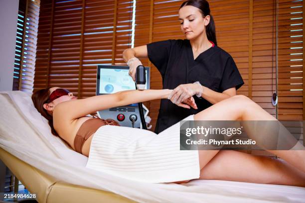 arm laser treatment in a spa setting - bare feet office stock pictures, royalty-free photos & images