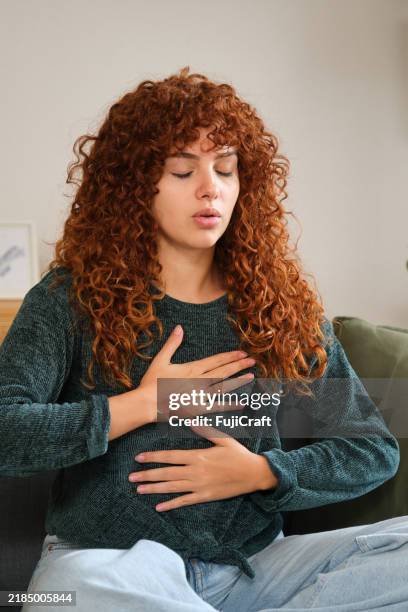 jeune femme pratiquant des exercices de respiration profonde à la maison - diaphragme photos et images de collection
