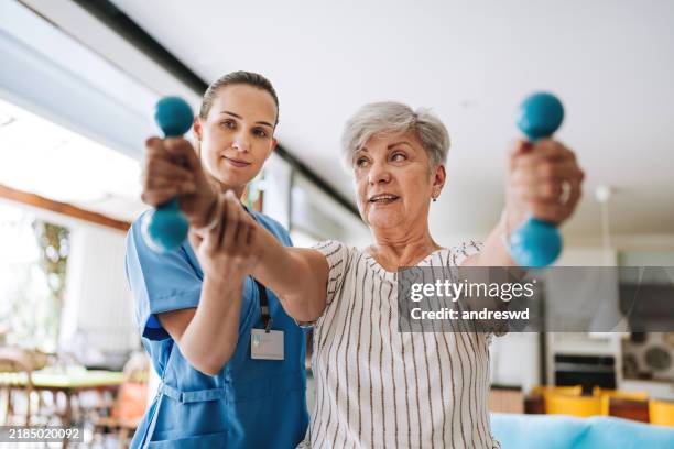 patient zu hause macht physiotherapie mit hantel - physiotherapie stock-fotos und bilder