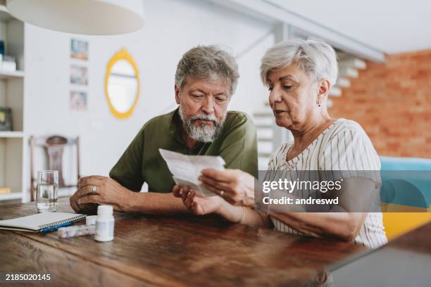 pareja de ancianos medicándose en casa con prescripción médica - medicare fotografías e imágenes de stock