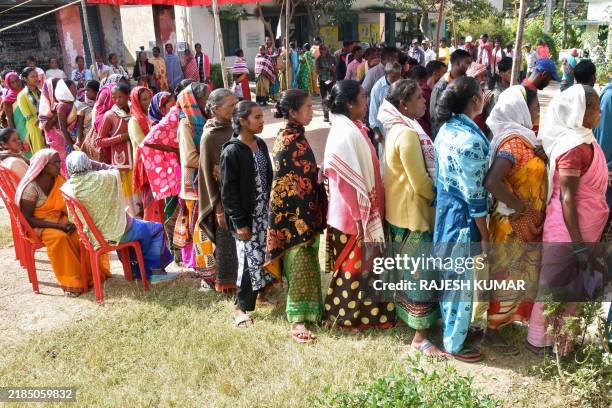 Voters stand in queues to cast their ballots at a polling booth during the Jharkhand state assembly elections on the outskirts of Ranchi, on November...