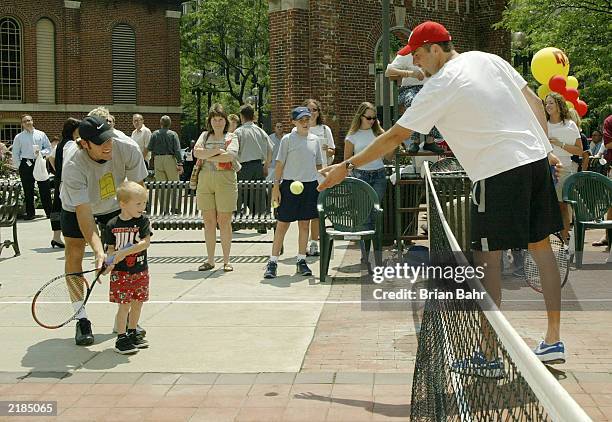 Justin Gimelstob tosses the ball to young Brian Maddox while Robby Ginepri helps as they try to draw attention to the 2003 RCA Championships by...