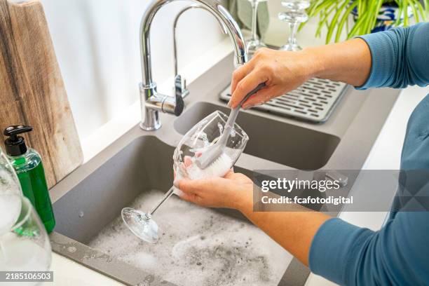 woman washing wineglass with a scrubbing brush and soap in kitchen sink - washing dishes stock pictures, royalty-free photos & images