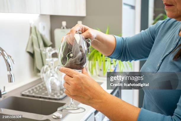 woman wipes and polishes a wine glass with a microfiber dish cloth in the kitchen - dish cloth stock pictures, royalty-free photos & images