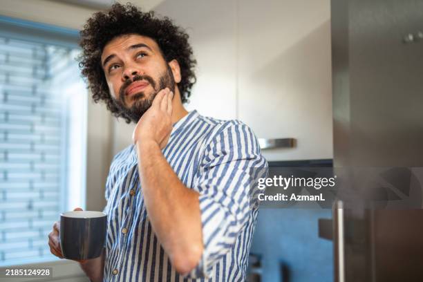 middle eastern man experiencing toothache at home - hopelessness stock pictures, royalty-free photos & images