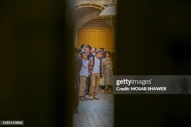 Group gathers near a gate under the watch of Israeli soldiers in the Old City area of Hebron, West Bank, as part of security measures to protect...